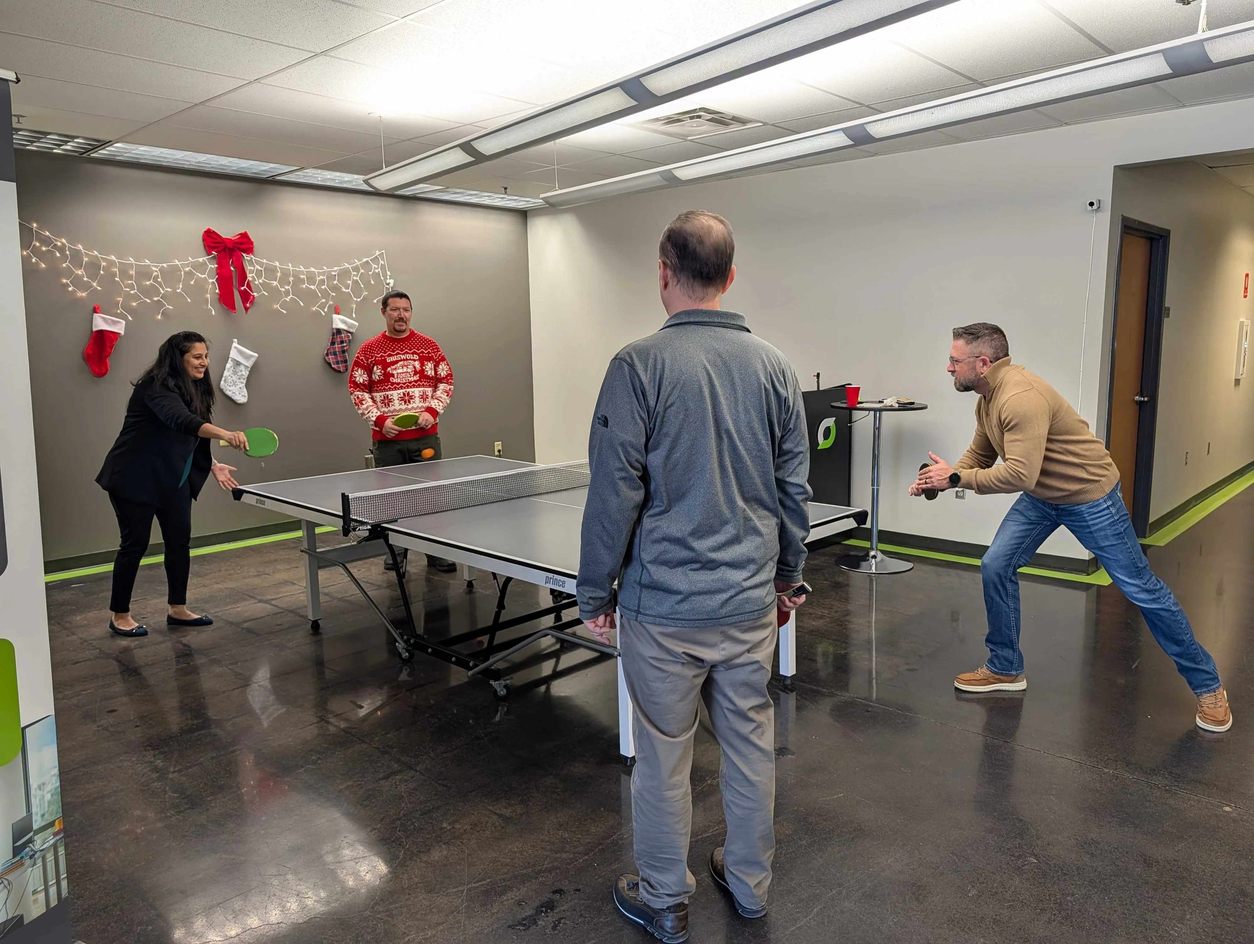 Team members playing ping pong at the 2025 holiday party